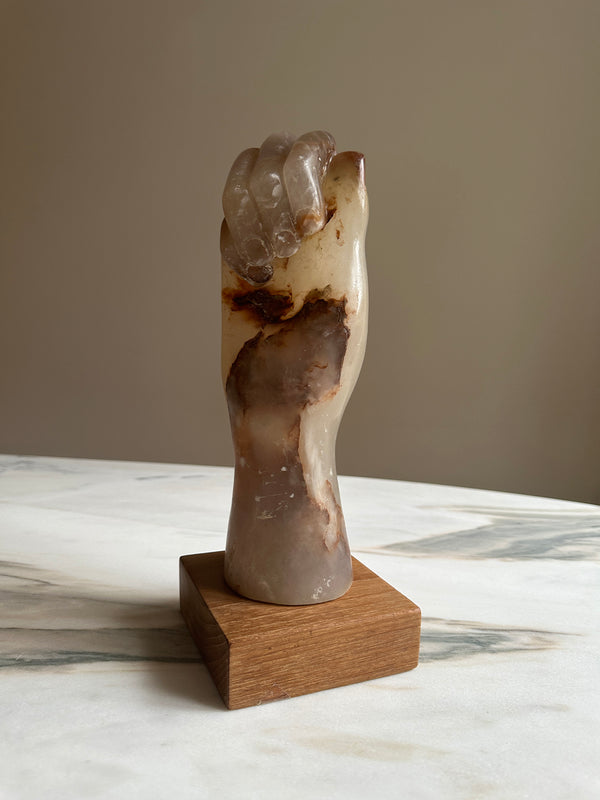 a carved onyx hand sculpture on a wooden base