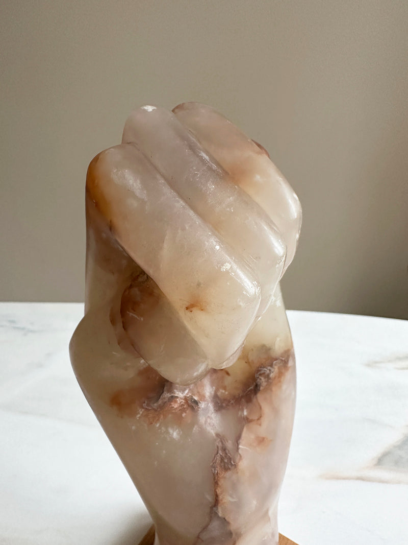 a carved onyx hand sculpture on a wooden base