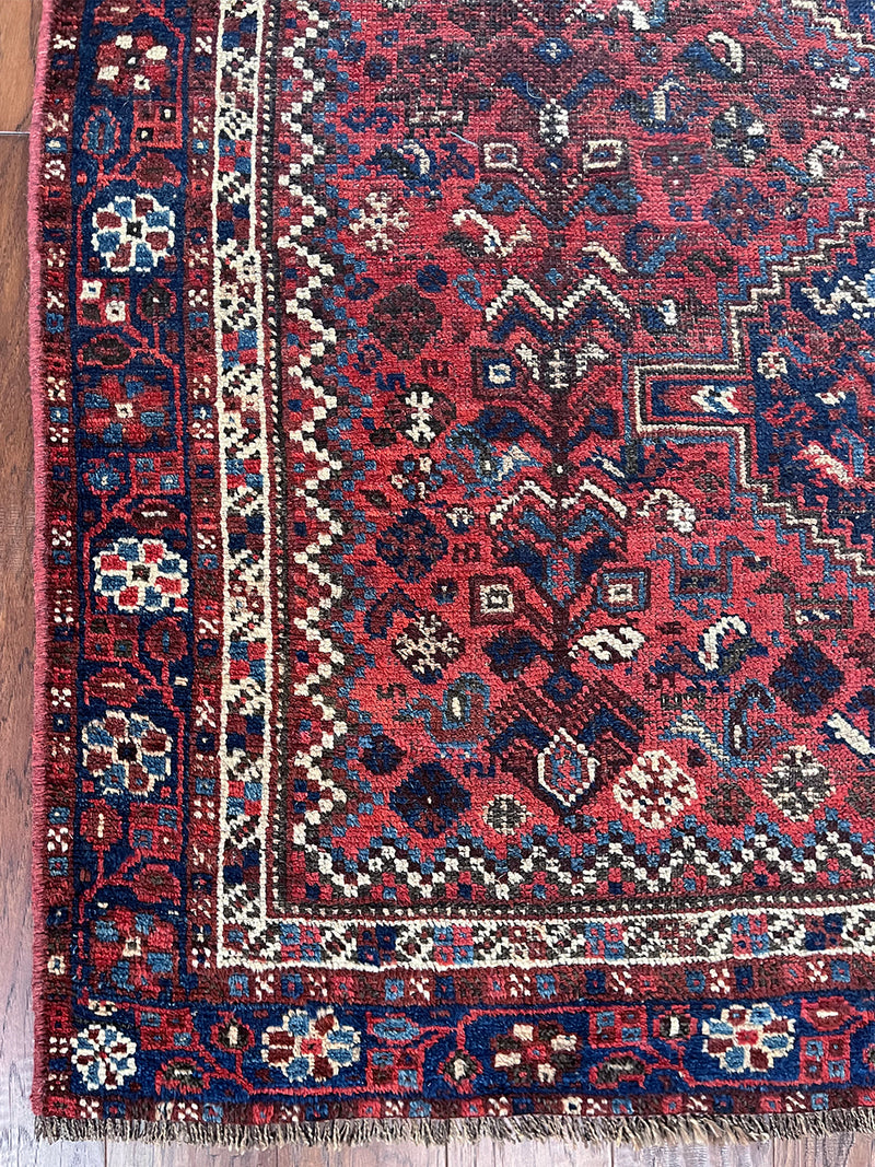 a vintage shiraz rug with a dark red field and dark blue medallions