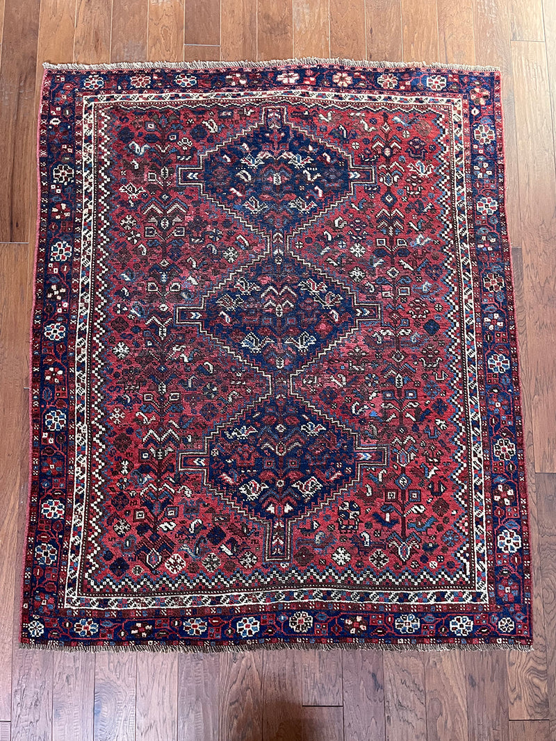 a vintage shiraz rug with a dark red field and dark blue medallions