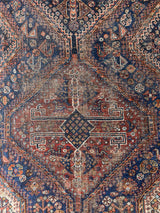 an antique qashqai rug with a beautiful navy blue field and a brick red border