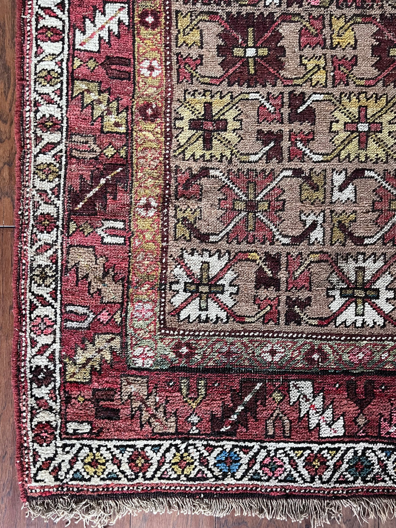 an antique bijar rug with yellow and brown flowers on a camel field