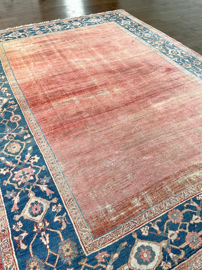 An antique heritage Bakshaish Serapi rug with a pretty peach field, natural abrash and a prussian blue border