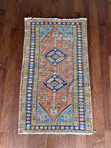 an antique heriz rug with a coral field and pretty pink, blue and lime green details