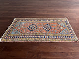 an antique heriz rug with a coral field and pretty pink, blue and lime green details