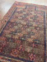 an antique baluch rug with a brick red field and blue details