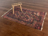 an antique baluch rug with a brick red field and blue details