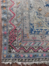 a large antique sumac rug with a purple field. blue medallions and hot pink accents