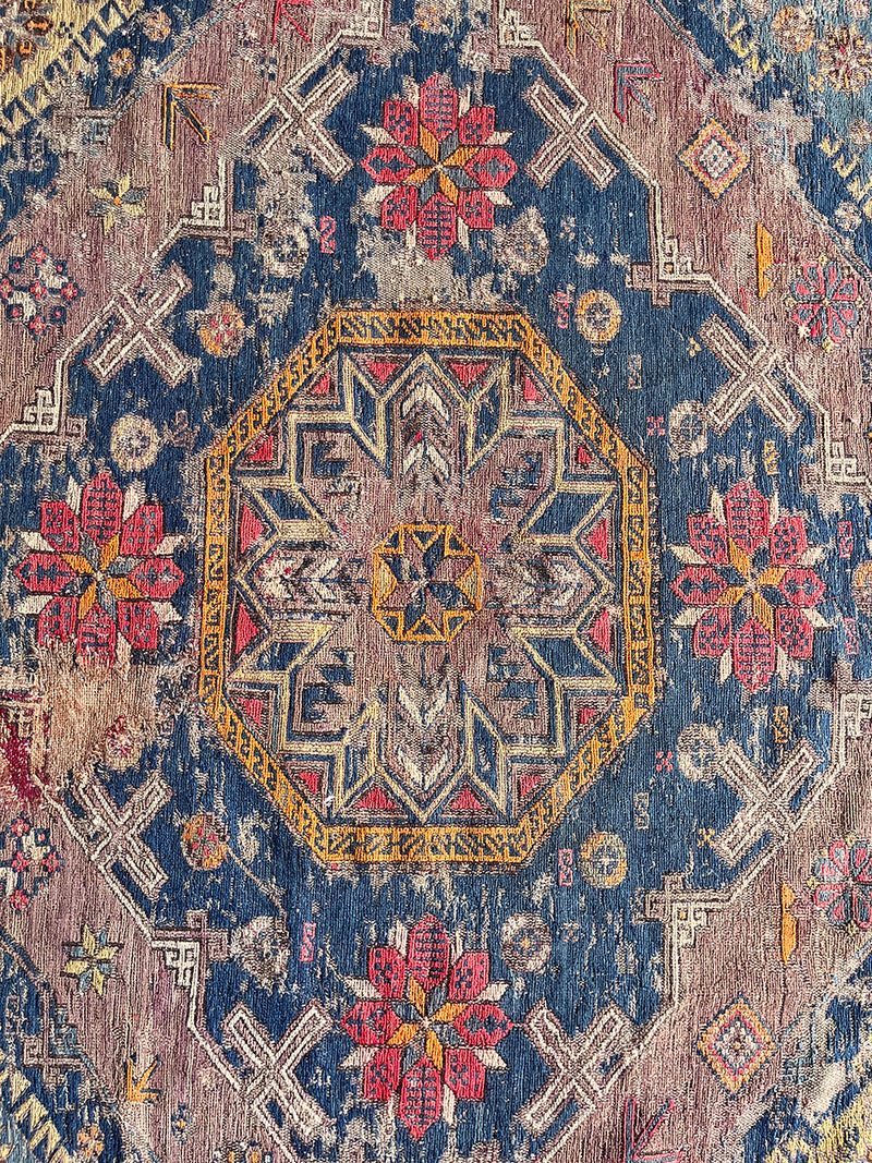 a large antique sumac rug with a purple field. blue medallions and hot pink accents