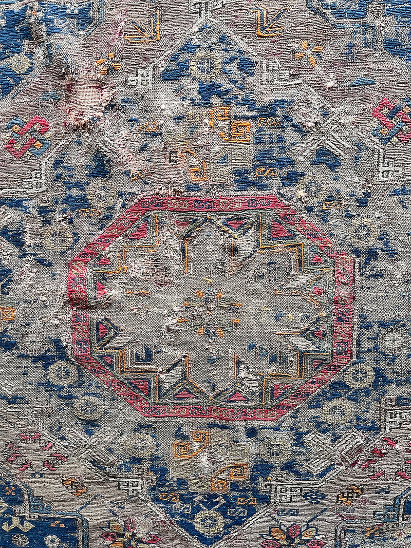 a large antique sumac rug with a purple field. blue medallions and hot pink accents