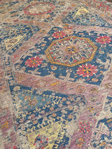 a large antique sumac rug with a purple field. blue medallions and hot pink accents