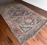 a large antique sumac rug with a purple field. blue medallions and hot pink accents