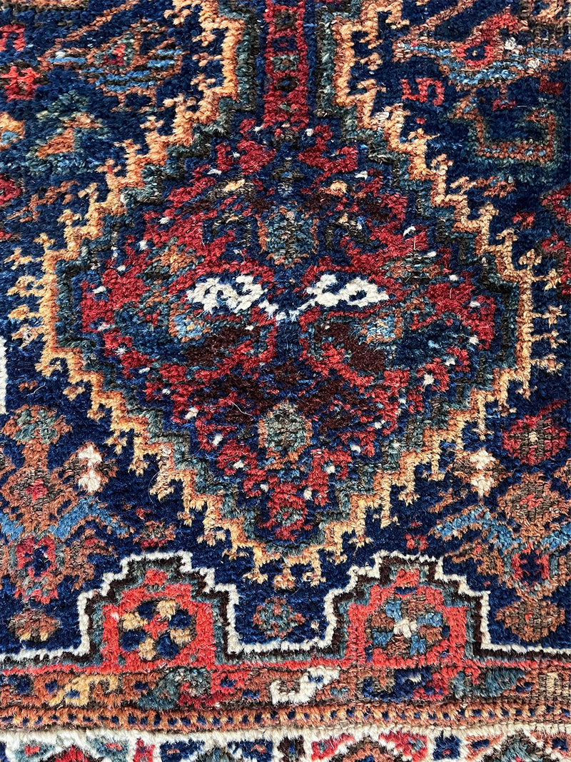 a mini antique shiraz rug with a dark blue and brick red palette