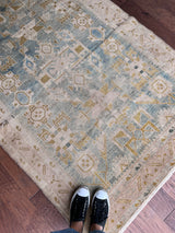 a vintage malayer rug with a faded sea green field with blue, white and lime green accents