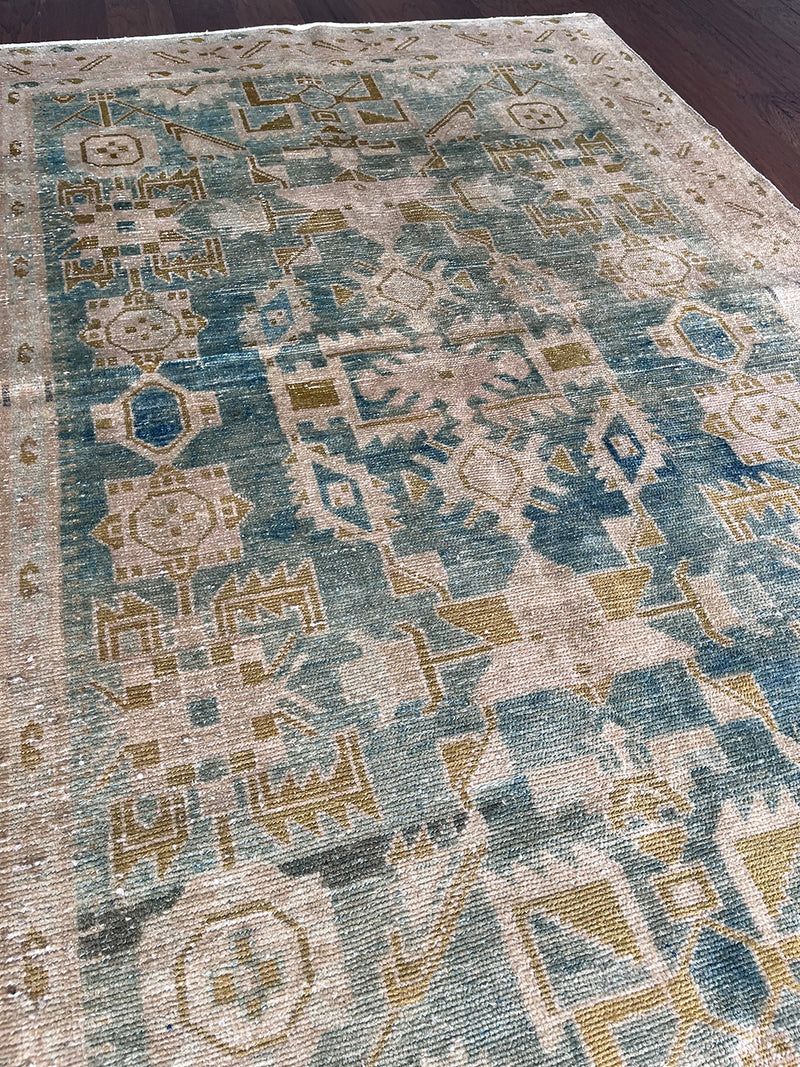 a vintage malayer rug with a faded sea green field with blue, white and lime green accents