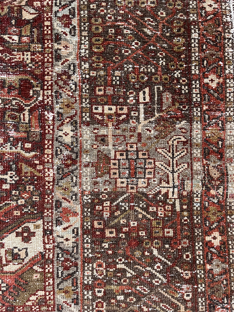 an antique heriz karajah rug with an earthy palette and warm red hues