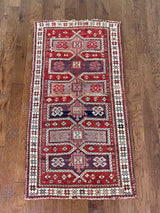an antique caucasian rug with a red field and medallions in lilac and dark purple