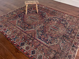 an antique qashqai rug with a dark blue field and warm brown details
