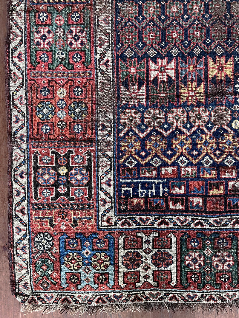 an antique shiraz qashqai with an intricate pattern, red border and midnight blue field
