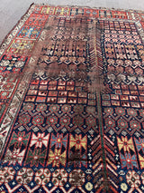 an antique shiraz qashqai with an intricate pattern, red border and midnight blue field