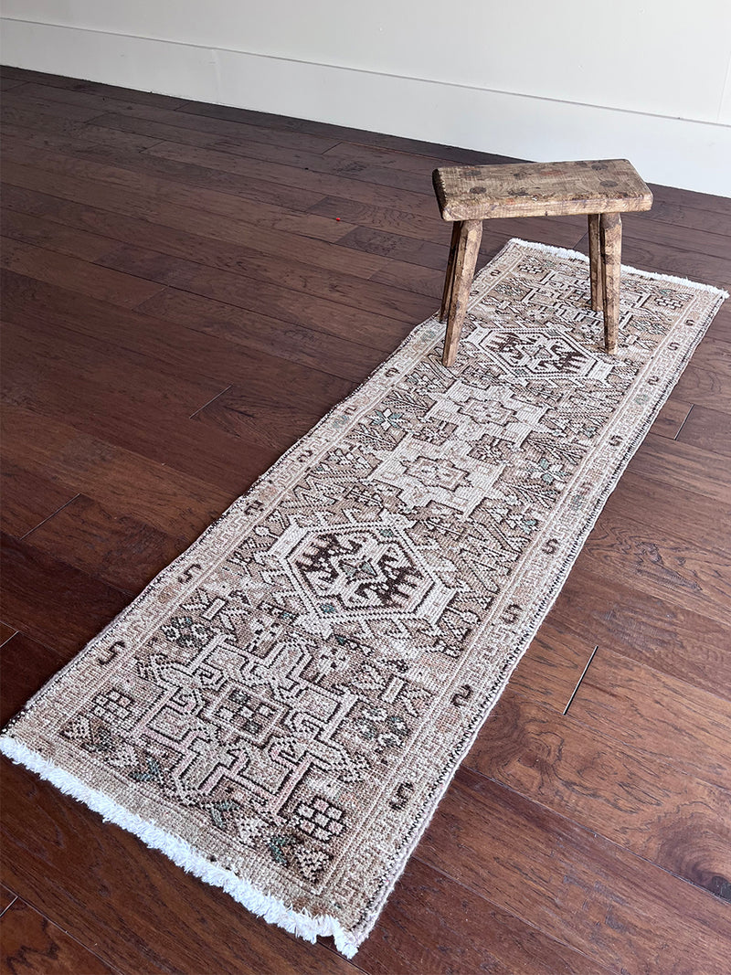 a mini vintage heriz runner with a neutral palette and subtle brown and teal accents