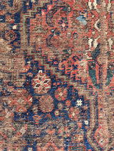 a small antique qashqai rug with a dark blue field, cream corners and red accents