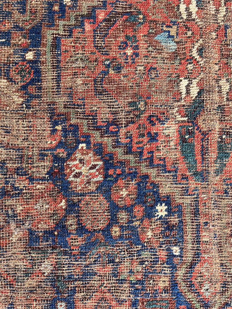 a small antique qashqai rug with a dark blue field, cream corners and red accents