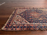 a small antique qashqai rug with a dark blue field, cream corners and red accents