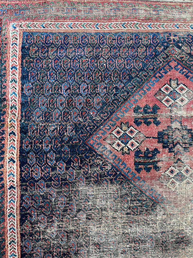 an antique afshar rug with a midnight blue field and a fine paisley pattern