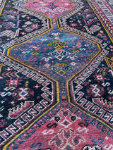 a vintage qashqai rug with a dark blue field and hot pink and yellow accents
