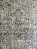 a vintage tabriz rug with a faded light sage green palette and a subtle floral pattern in brown and taupe