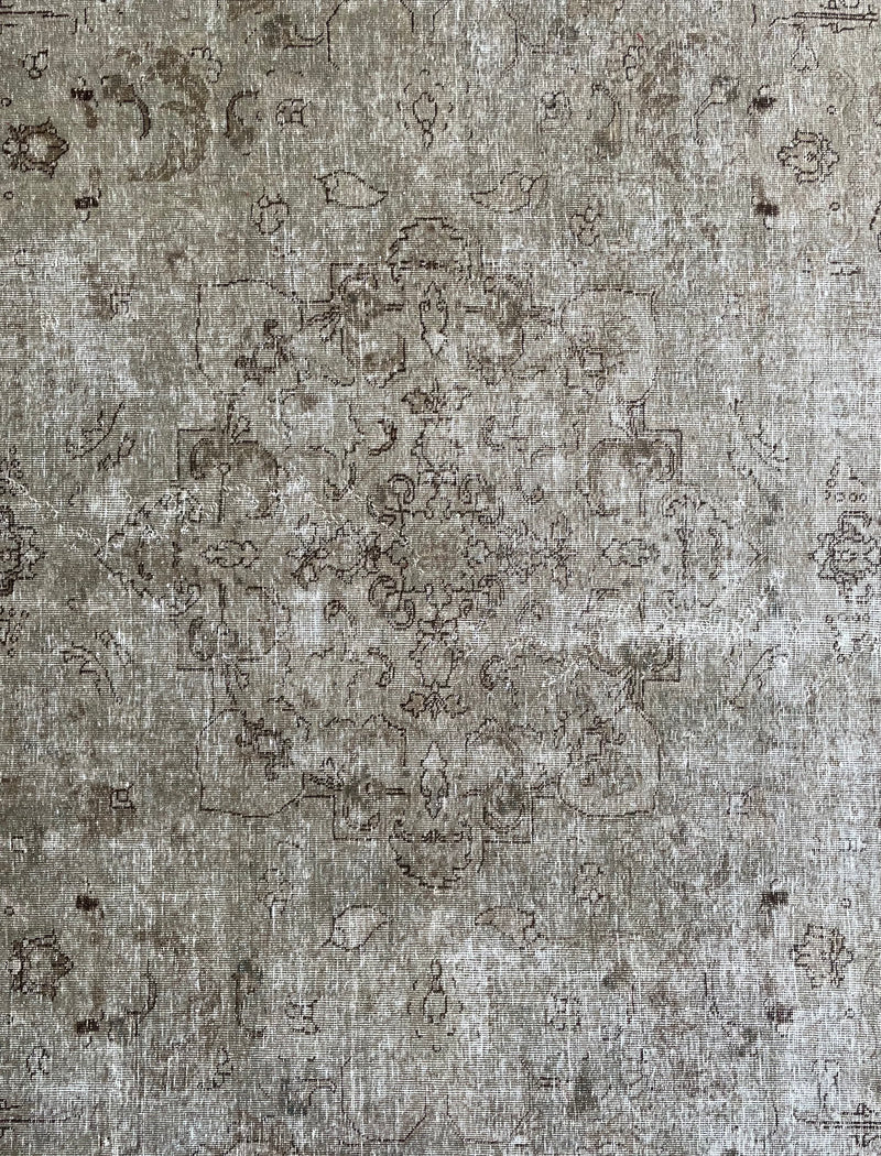 a vintage tabriz rug with a faded light sage green palette and a subtle floral pattern in brown and taupe