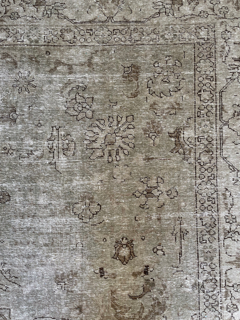 a vintage tabriz rug with a faded light sage green palette and a subtle floral pattern in brown and taupe