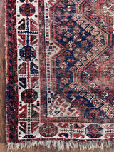 an antique qashqai rug with dark blue field and brown and red accents