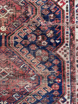 an antique qashqai rug with dark blue field and brown and red accents