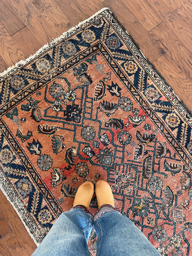 an antique bakshaish rug with a salmon pink field and green and teal floral pattern
