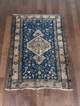an antique malayer rug with a blue field, camel-colored medallion and border