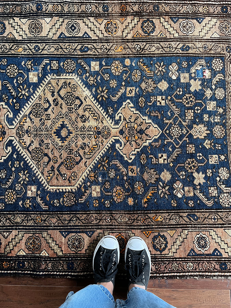 an antique malayer rug with a blue field, camel-colored medallion and border