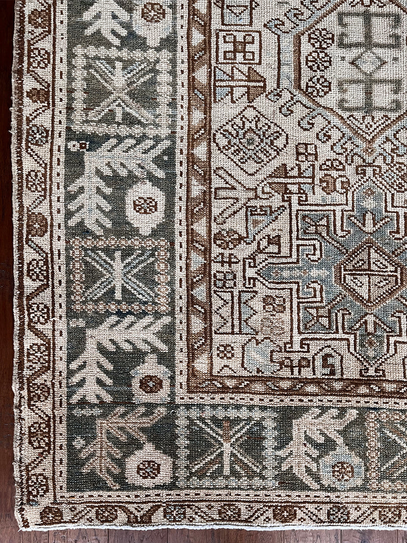 a large heriz karajah rug with blue and brown accents and multiple medallions