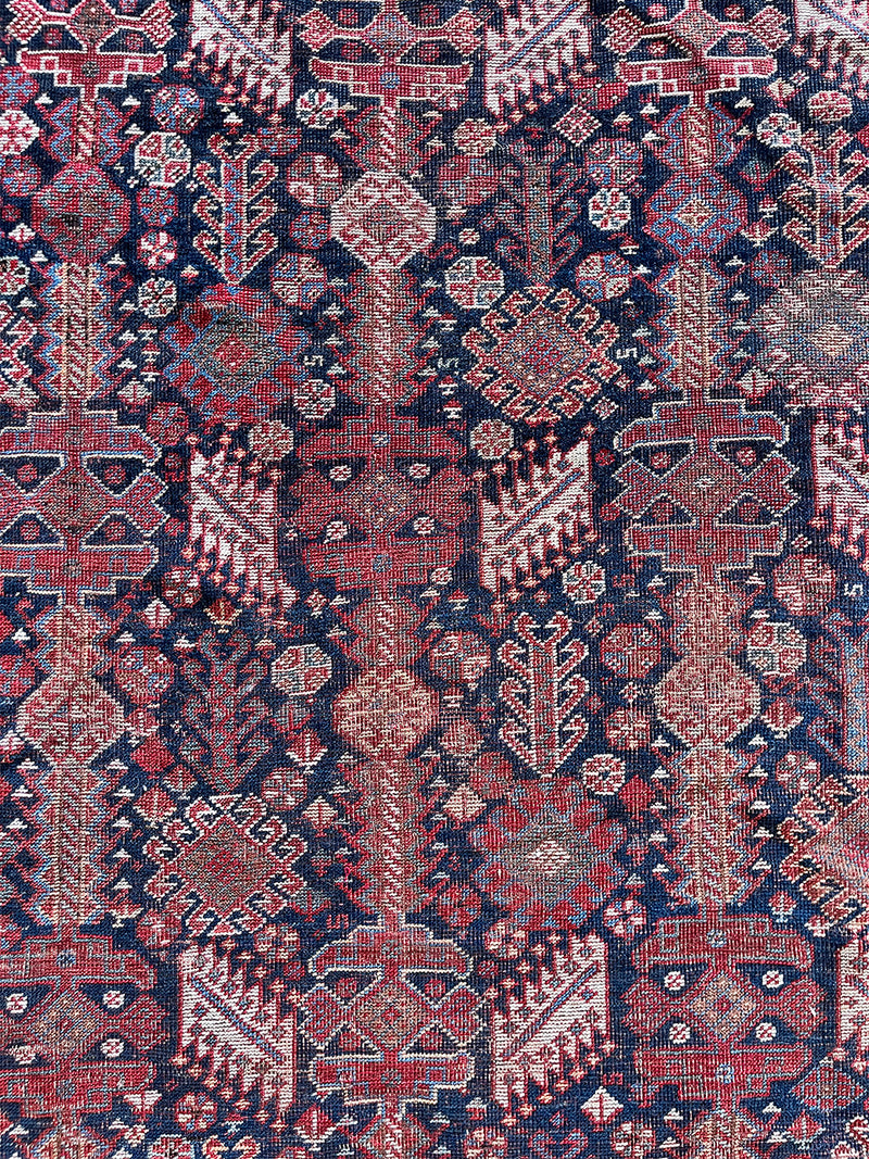 an antique qashqai rug with a midnight blue field and white, yellow and red accents 