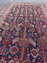 an antique qashqai rug with a midnight blue field and white, yellow and red accents 