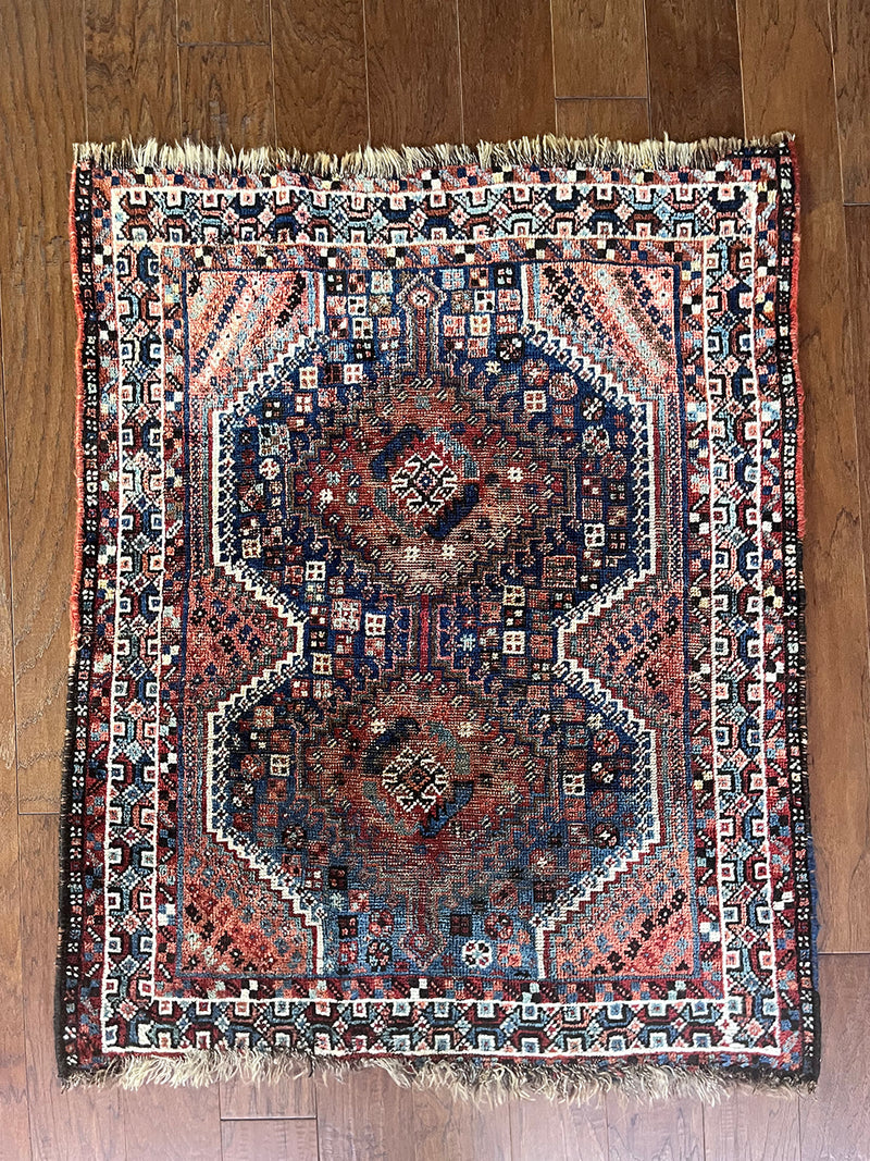 an antique qashqai rug with a blue field and pink and lilac details