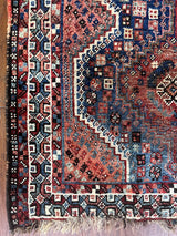an antique qashqai rug with a blue field and pink and lilac details
