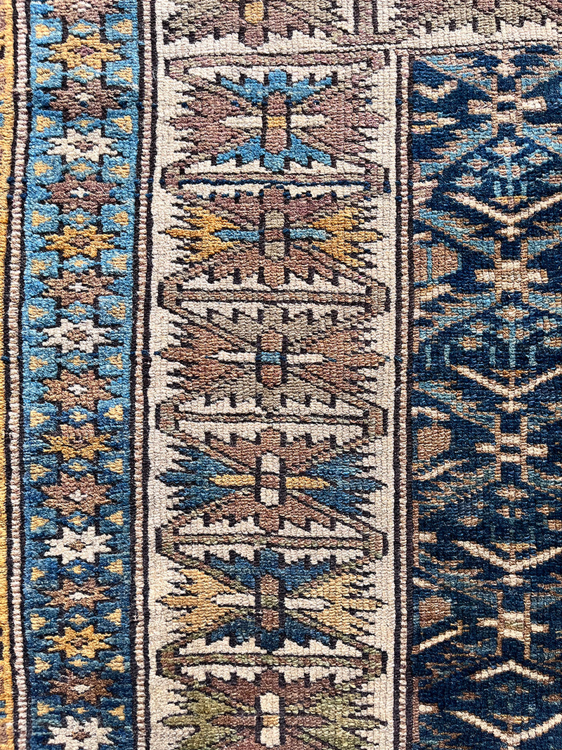 an antique caucasian kuba rug with a navy blue field and brown accents