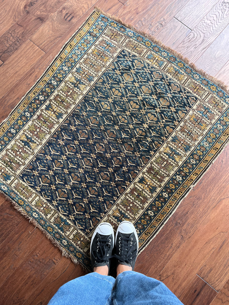 an antique caucasian kuba rug with a navy blue field and brown accents