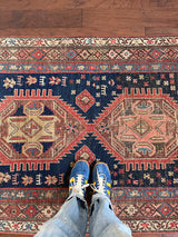 an antique kurdish rug with a blue field and coral and yellow accents in a geometric pattern