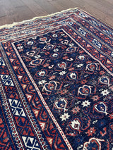 an antique caucasian shirwan rug with a navy blue field and a red border