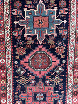 an antique heriz karajah runner with a dark blue field and pink and teal medallions
