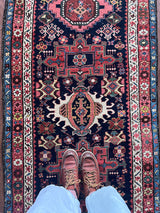 an antique heriz karajah runner with a dark blue field and pink and teal medallions