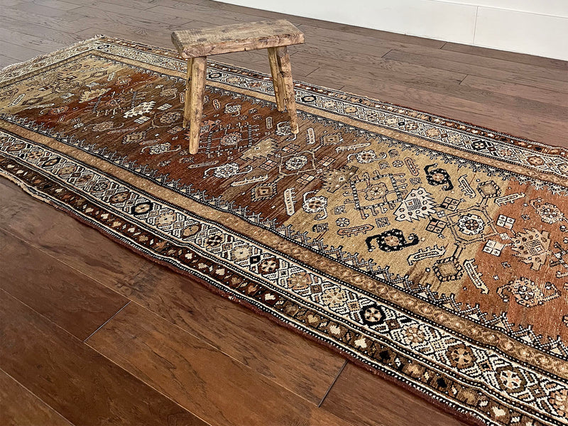 an antique northwest persian runner with a camel, taupe and coral palette and a cream border